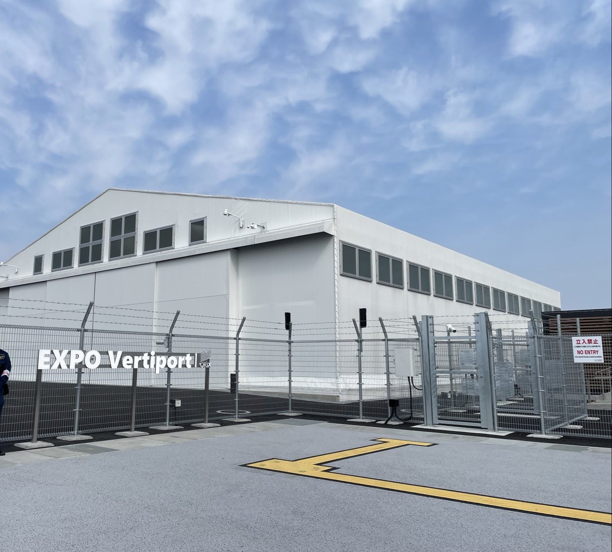 万博会場のEXPO Vertiportの格納庫と、フェンスに掲げられたEXPO Vertiportの看板。手前は立ち入りできない区域になっている