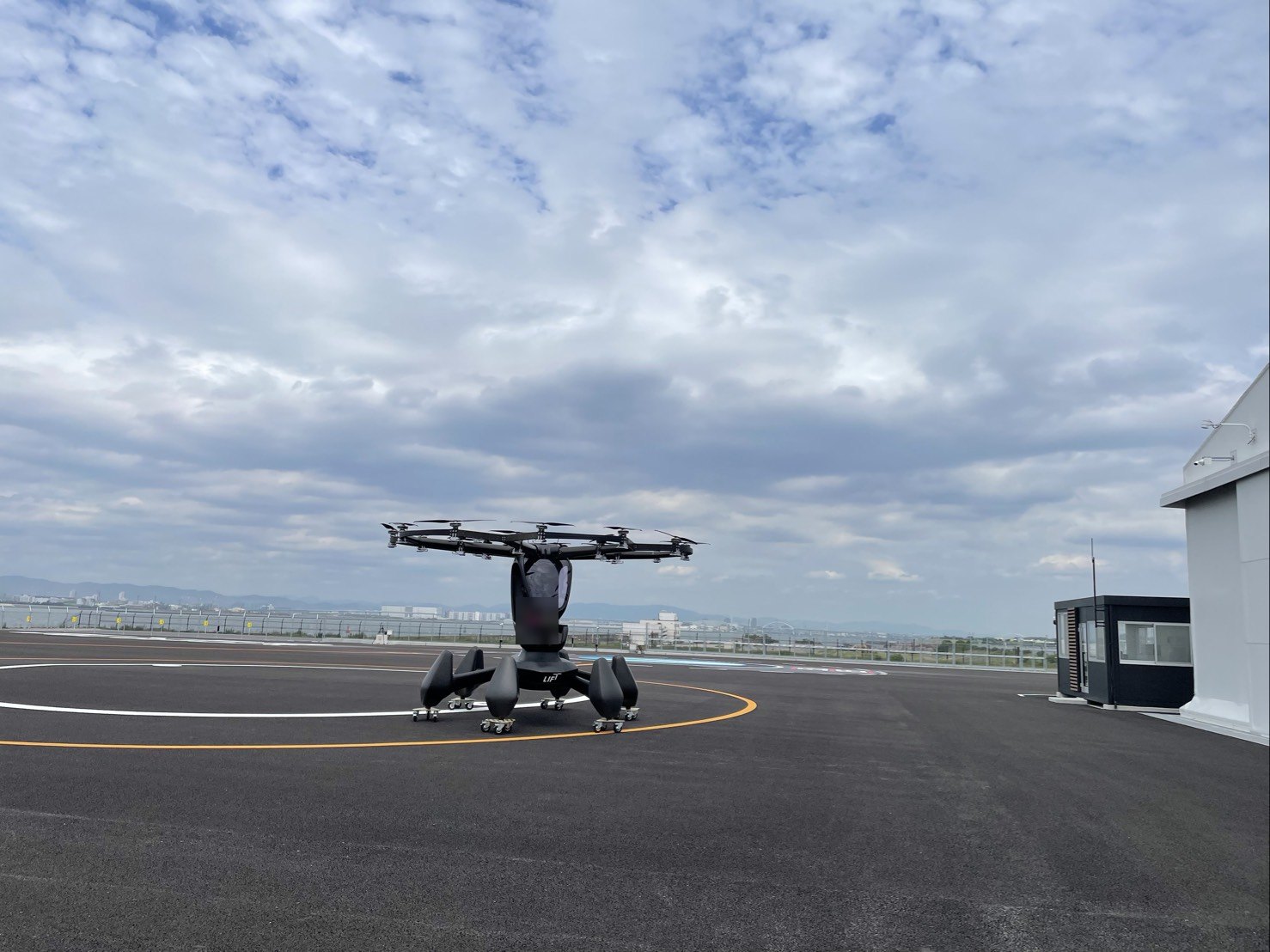 EXPO Vertiportの発着場の円の上に置かれたHEXAの実機。1人乗りの座席の上に、小さなプロペラが輪のように並んでいる