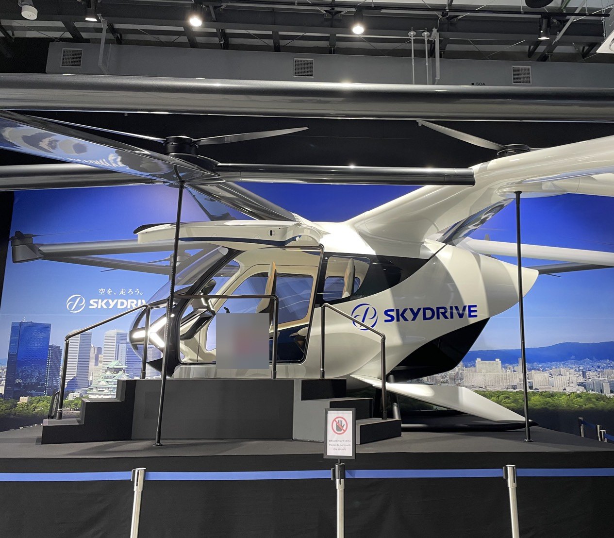万博のパビリオンに展示されていたSkyDriveの機体のモックアップ。白い機体に客室と複数のプロペラがある